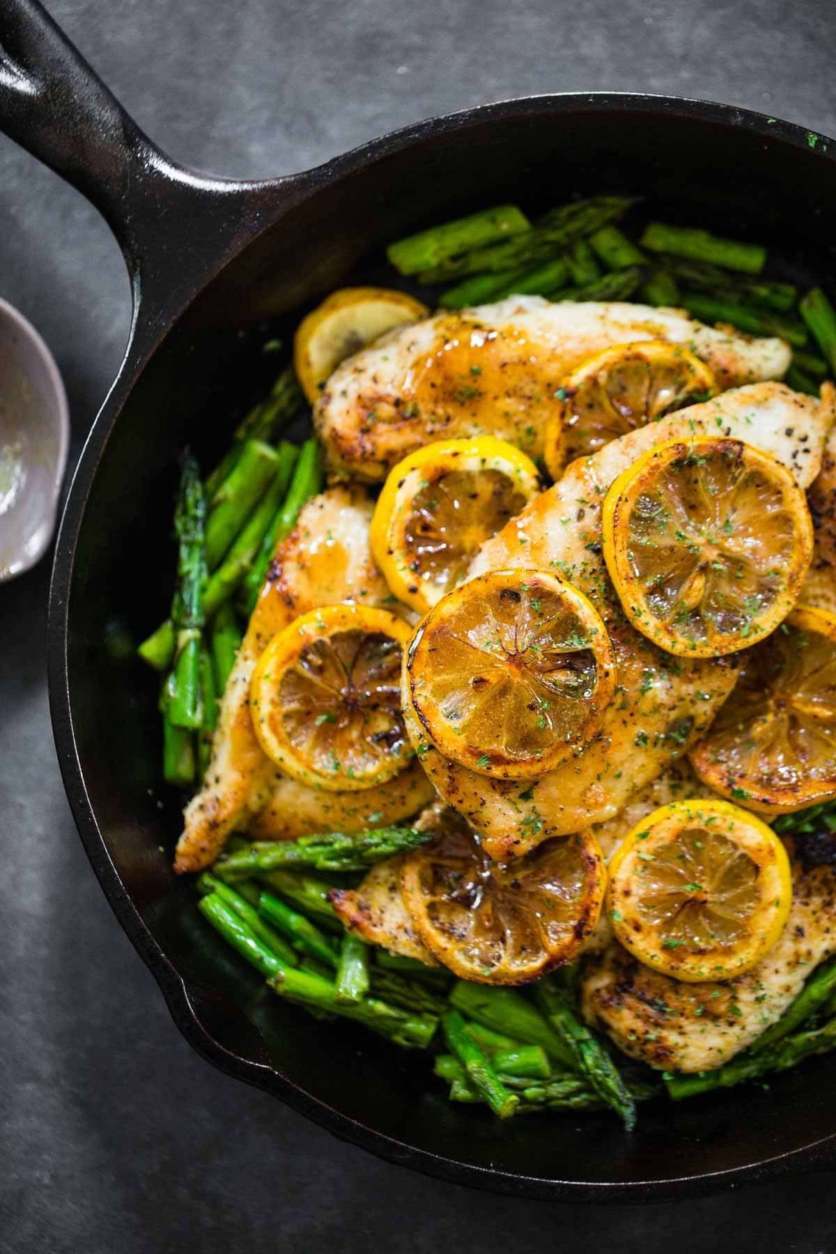 Lemon chicken with asparagus in a pan.