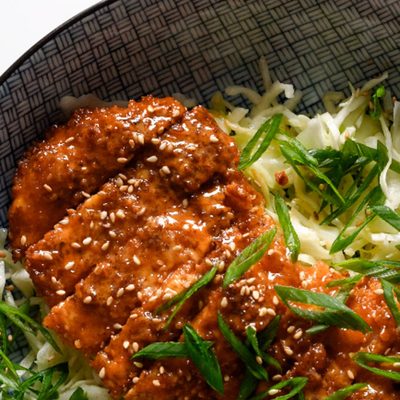 Gochujang chicken on a bowl of shredded cabbage.