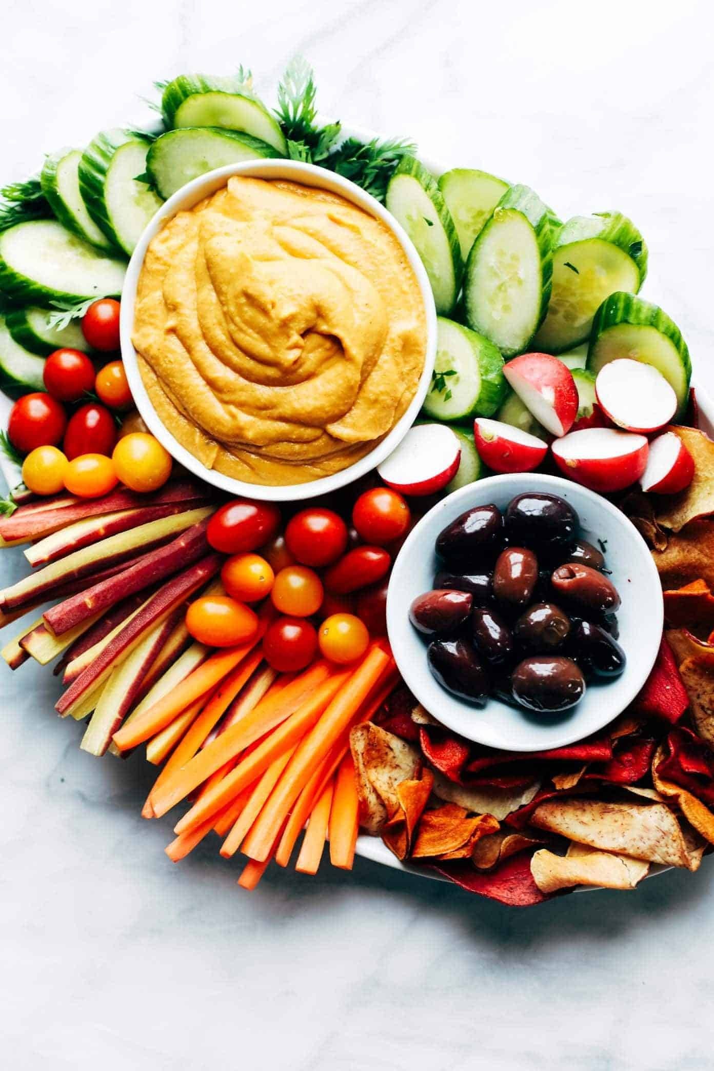Curry hummus on a plate with veggies and olives.