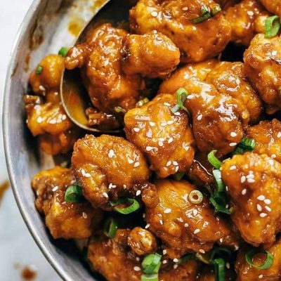 General Tso's Cauliflower in a pan with a spoon.