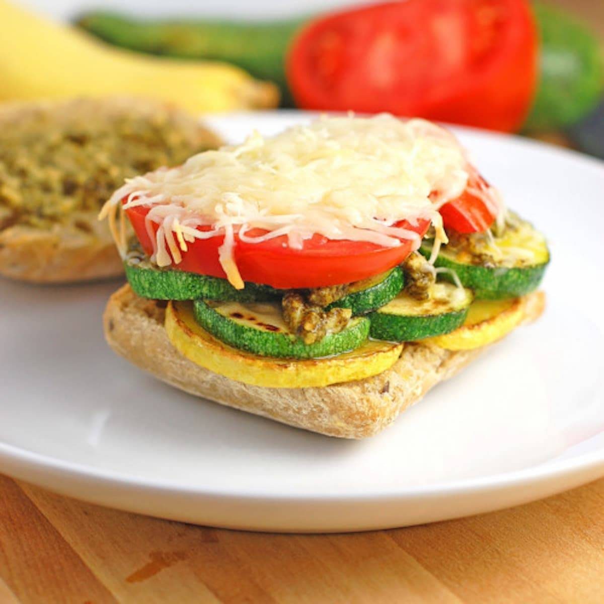 Parmesan and pesto grilled veggie sandwich on a white plate.