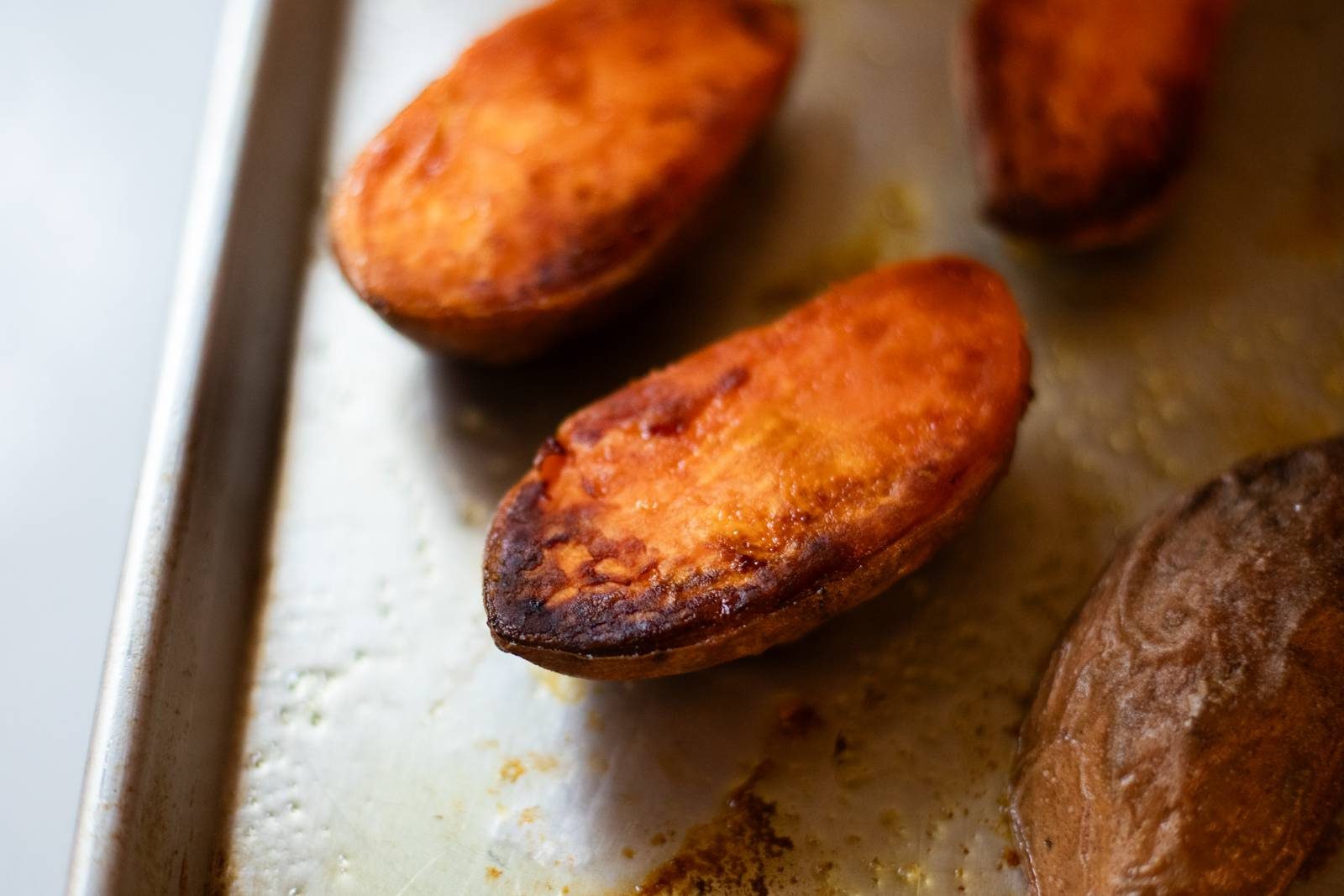 Roasted sweet potatoes on a sheet pan.