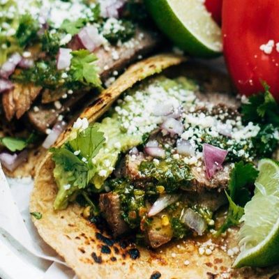 Steak Tacos on plates with hand squeezing a lime.