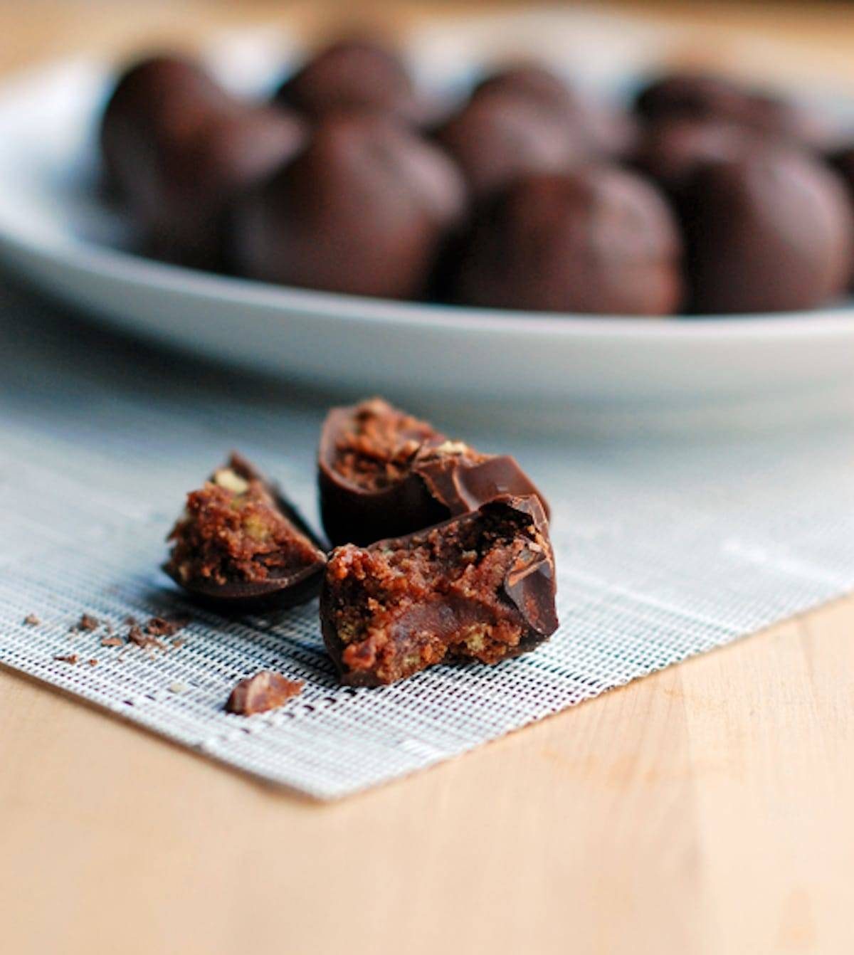 Triple chocolate party balls on a plate and one ball in pieces on a placemat. 