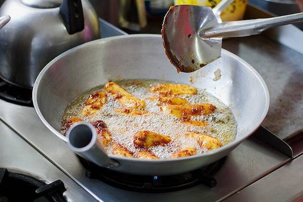 Bananas frying in a pan of oil.