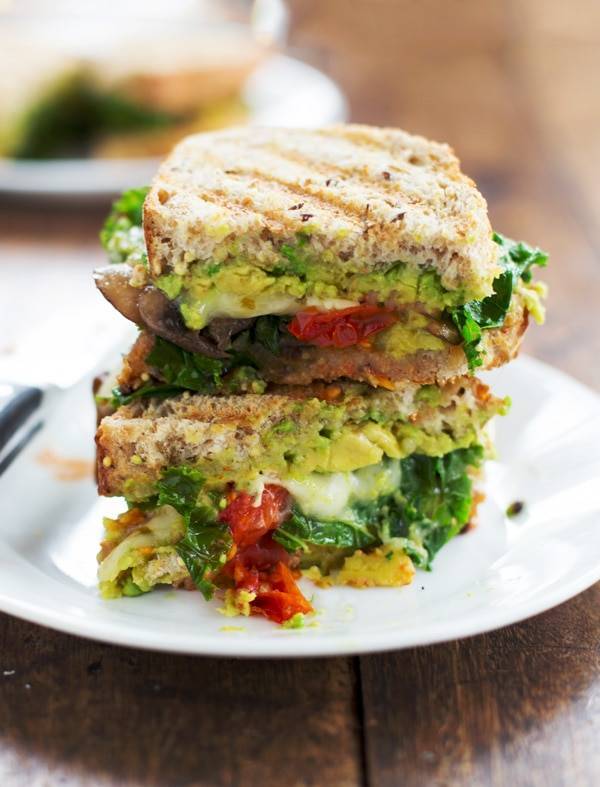 Avocado veggie panini stacked on a white plate.