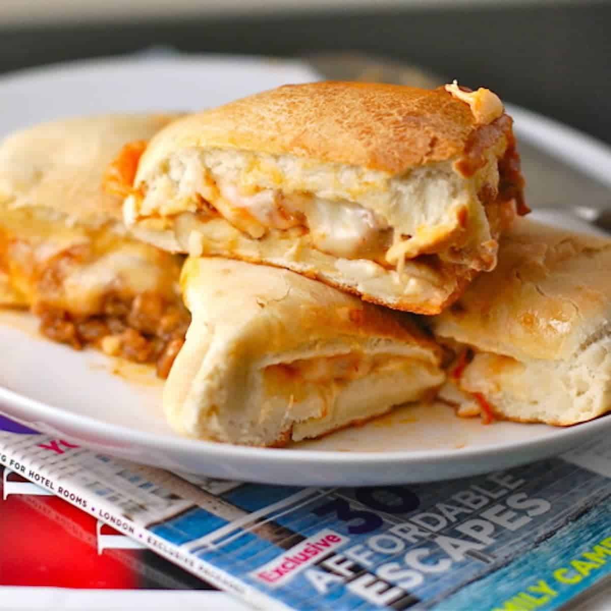 Sausage and mozzarella calzones on a white plate.