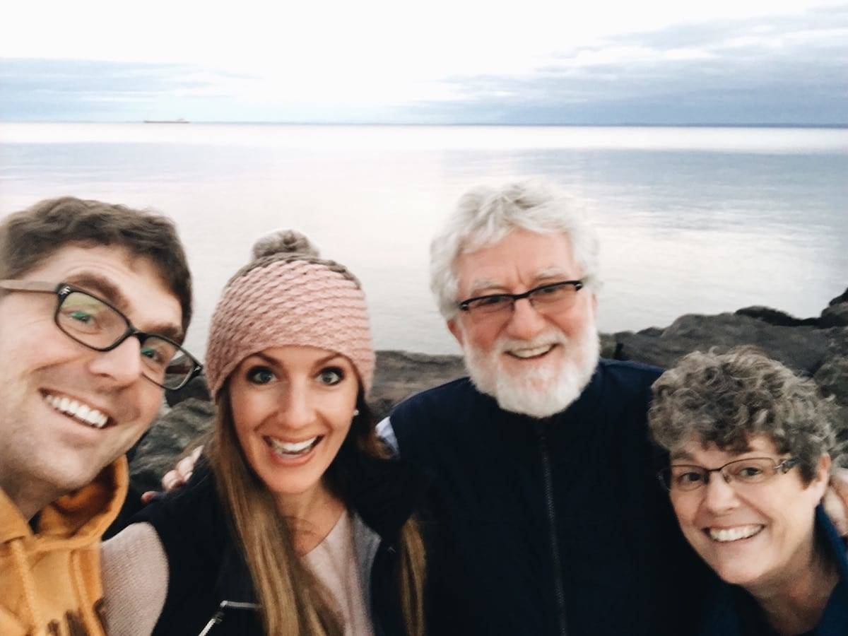 People smiling at a camera near the lake.